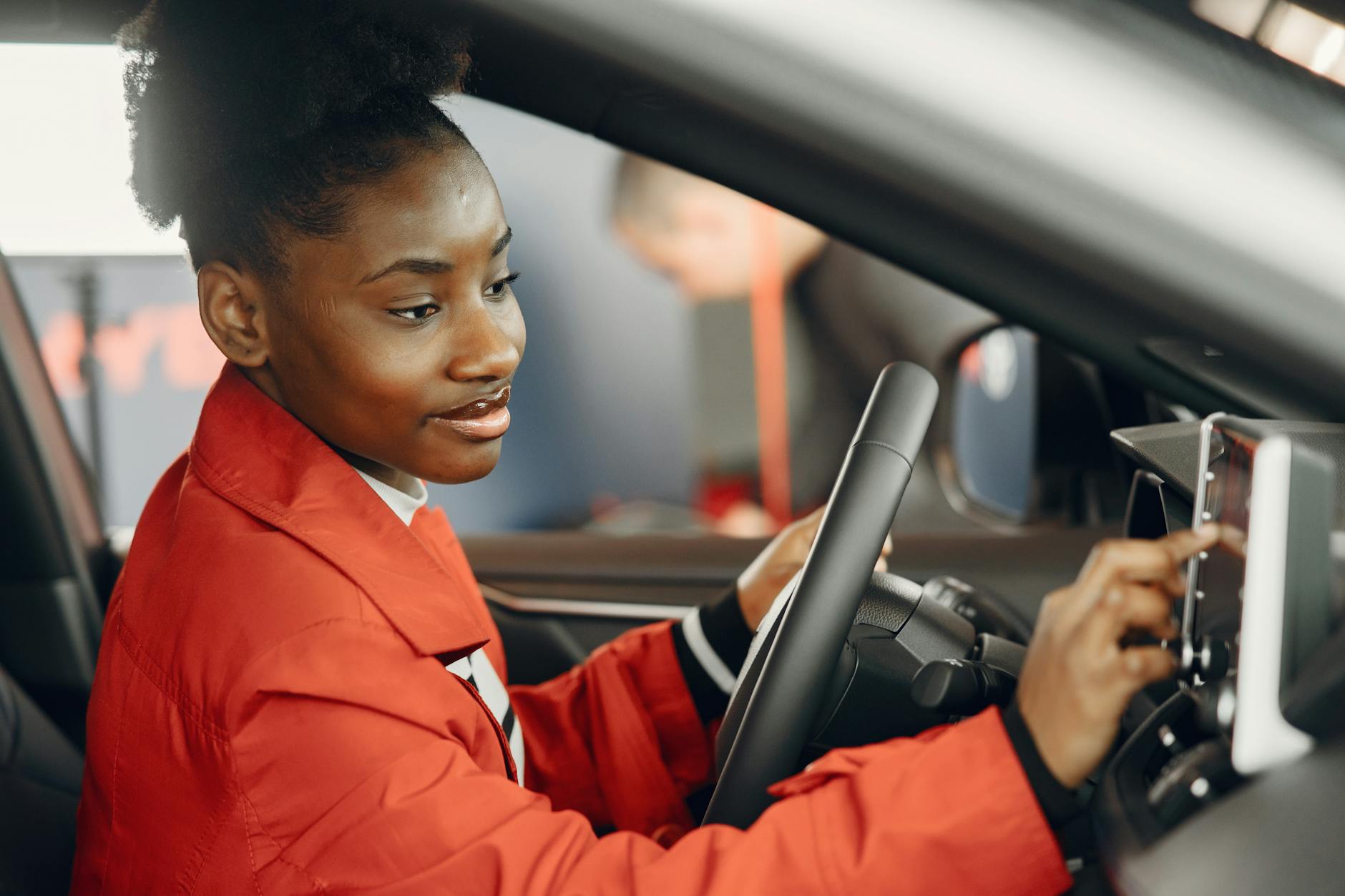 Kobieta w czerwonym płaszczu dotyka ekranu dotykowego na desce rozdzielczej