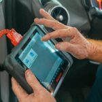 Mechanik diagnozuje silnik samochodu skanerem OBD wewnątrz kabiny