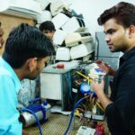 Uczestnicy szkolenia naprawy klimatyzacji samochodowej przy aucie