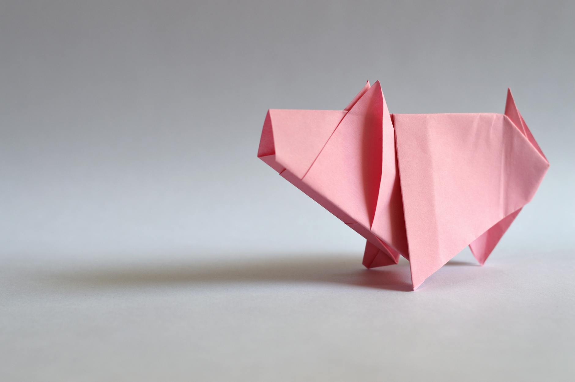 Różowa papierowa świnka origami na jasnym tle
