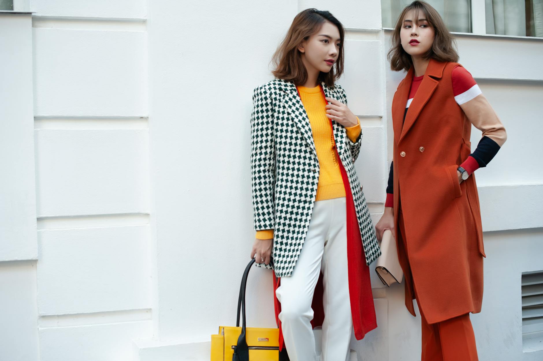 Eleganckie kobiety w jesiennych płaszczach na tle nowoczesnego miasta