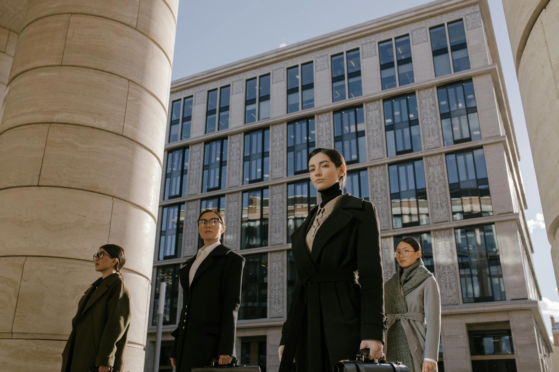 Eleganckie kobiety w różnych płaszczach spacerują po nowoczesnym mieście