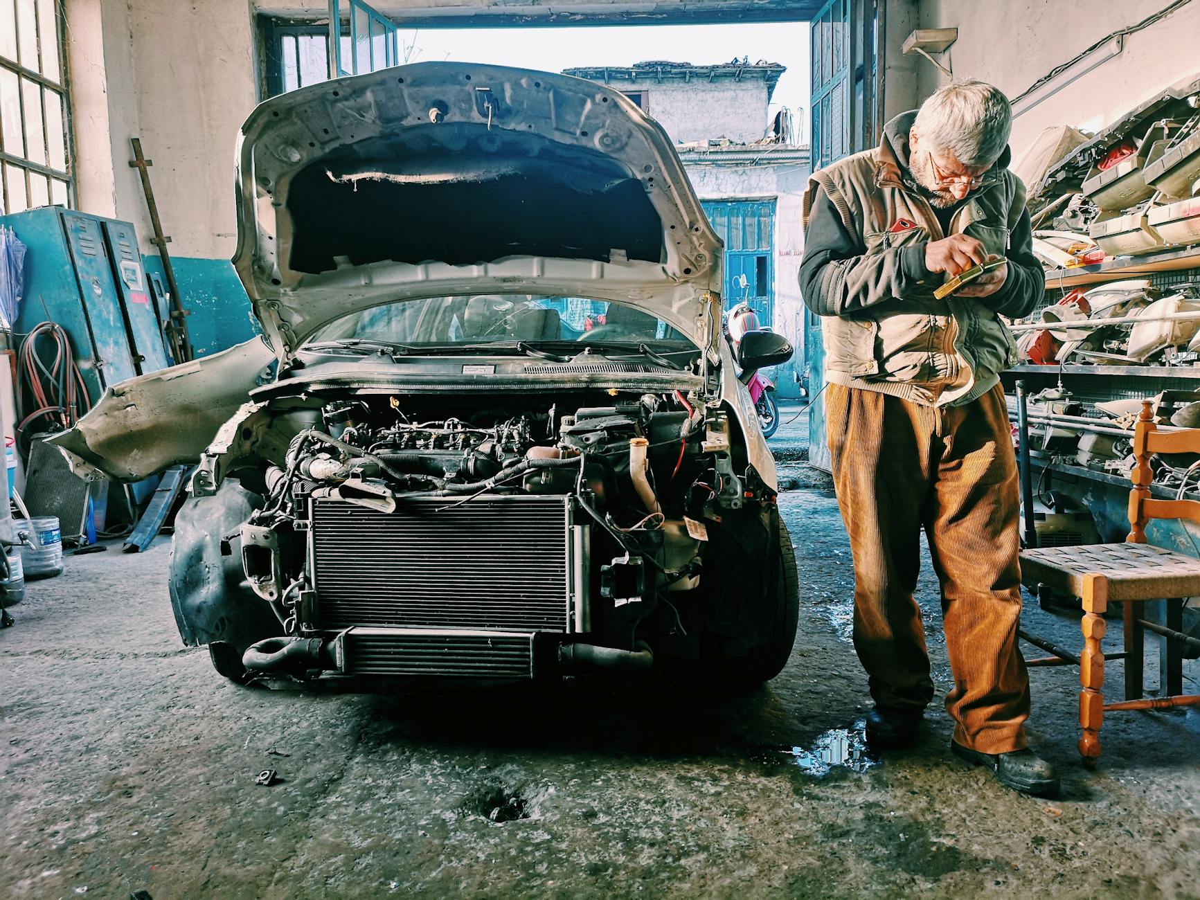 Mechanik naprawiający silnik auta w warsztacie z otwartą maską