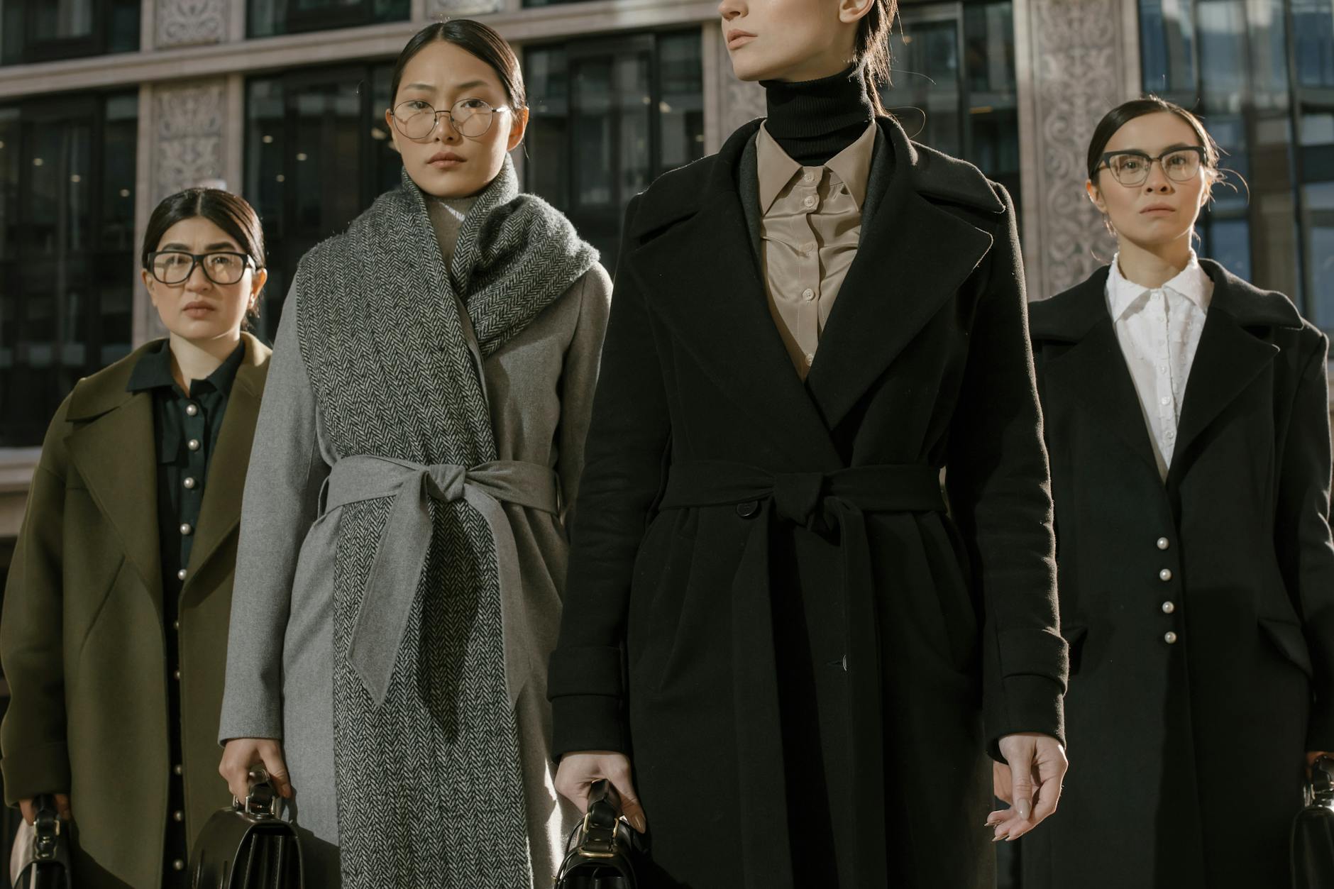 Stylowe kobiety w płaszczach pozują na ulicy w mieście