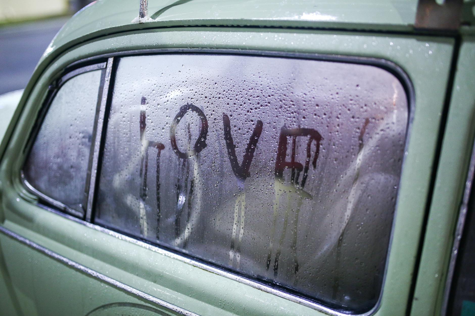 Napis love na zaparowanej szybie starego auta jesienią