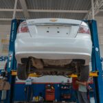 Biały Chevrolet podniesiony na podnośniku w warsztacie samochodowym