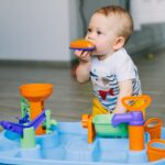 Niemowlę gryzie plastikową zabawkę podczas zabawy w domu