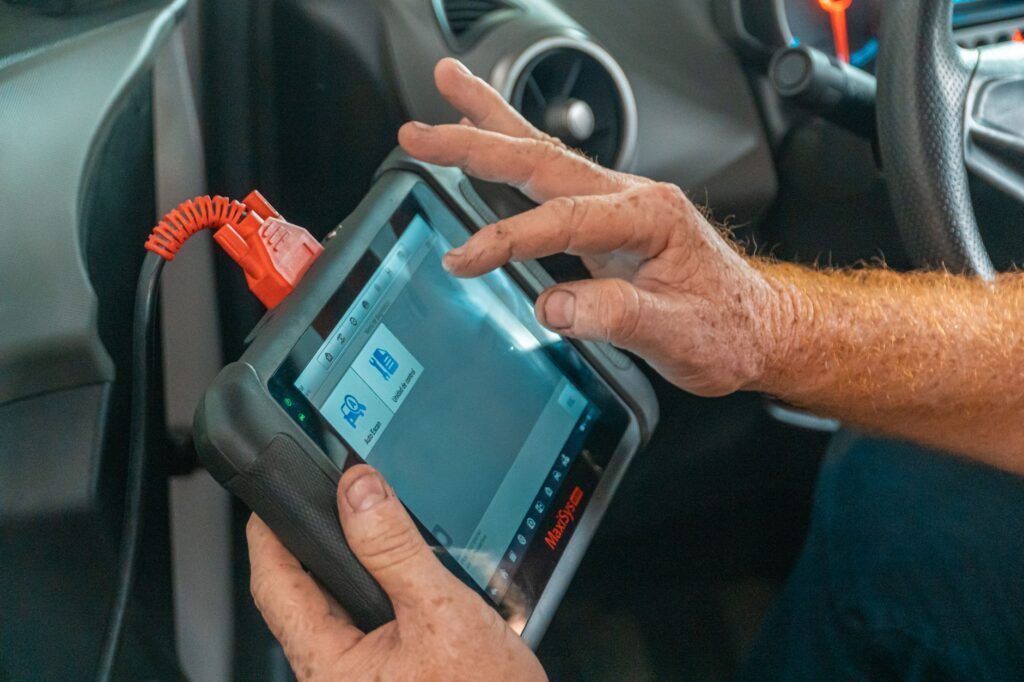 Mechanik diagnozuje usterkę silnika testerem wewnątrz samochodu